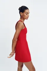 Vestido corto de color rojo con escote corazón estilo corsetero, tirantes anchos y falda con corte evasé. Cuenta con cierre de cremallera oculto en la espalda.
