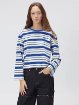 Remera de manga larga con diseño a rayas horizontales en tonos azul, blanco y negro. Presenta un cuello redondo al tono y un logo bordado en el pecho. El diseño destaca por tener un patrón de rayas diferente en las mangas y un calce holgado.