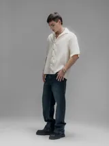 Camisa de manga corta color blanco roto, con cuello clásico y cierre frontal de botones.