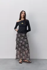 Remera de manga larga negra con calce al cuerpo y escote amplio tipo bote que deja los hombros al descubierto.