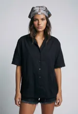 Camisa negra de manga corta con cuello tipo solapa y botones frontales. Presenta bordados sutiles en tono negro en las mangas y en la parte inferior delantera.