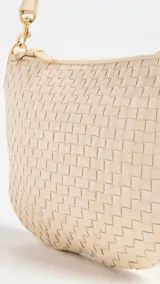 Bandolera color crema, tejida a mano, con correa al hombro de cuero color beige y cierre superior con cremallera.