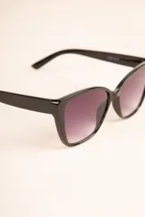 Lentes de sol negros con forma de ojo de gato y cristales degradados.