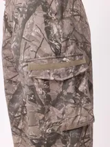 Pantalon cargo de corte recto y tiro medio, con estampado de camuflaje tipo bosque en tonos beige y marrones. Cuenta con bolsillos laterales tipo cargo con solapa y cierre de botón.