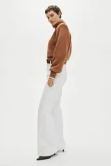 Pantalón acampanado de sarga de algodón color blanco, de tiro alto con pliegues en las piernas y bolsillos decorativos delanteros. Incluye cinturón marrón.