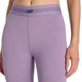 Calza deportiva New Balance color lila, de tiro alto con cintura elástica ancha que incluye el logo de la marca y líneas sutiles. Confeccionada con tejido elástico con tecnología NB Sleek para mayor comodidad y ajuste firme durante el entrenamiento.