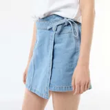 Falda pantalón vaquera de corte cruzado en color azul claro, con detalle de lazo en la cintura.