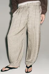Pantalón de tiro medio con diseño de cuadros vichy en tonos neutros. Presenta pierna ancha, cintura elástica ajustable con cordones, bolsillos laterales y detalle de pinzas en el delantero.