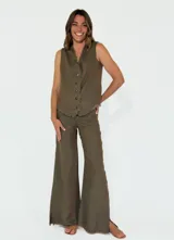 Pantalon de corte recto y pierna ancha, confeccionado en lino color beige. Presenta un diseño de tiro medio con aberturas laterales en el ruedo y detalle de bordes desflecados.