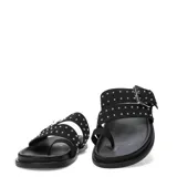 Sandalias Miss Carol modelo Talira de color negro, con diseño plano, tiras dobles decoradas con tachas metálicas plateadas, hebilla ajustable y tira separadora para el dedo.