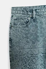 Jeans de tiro alto con corte flare y diseño de tejido jacquard con patrón floral. Presenta cinco bolsillos, trabillas en la cintura y cierre frontal con cremallera y botón.