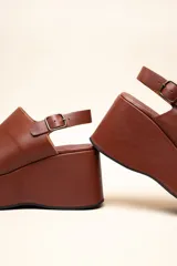 Sandalias con plataforma color marrón, con capellada envolvente, pulsera trasera ajustable y hebilla metálica.