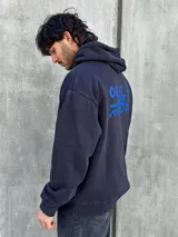 Canguro negro con capucha ajustable con cordones, bolsillo tipo canguro y logo bordado en azul en el pecho.