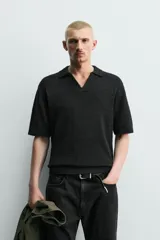 Polo de punto color negro con textura irregular, cuello solapa con abertura frontal, manga corta y acabados en rib, de corte relaxed fit.