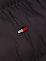 Chaleco negro acolchado con cuello alto y cierre de cremallera. Cuenta con dos bolsillos laterales y logo de Tommy Hilfiger bordado en el pecho.