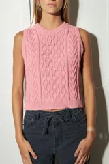 Chaleco de tejido de punto color marrón oscuro, con diseño de ochos y rombos en relieve. Tiene cuello redondo y es sin mangas.