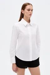 Camisa de algodón blanca, de corte entallado al cuerpo, con cuello camisero, manga larga y cierre frontal de botones.