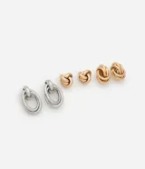 Set de tres pares de aros de metal con diferentes diseños: aros colgantes con doble aro ovalado plateado, aros tipo botón con nudo pequeño dorado y aros tipo botón con nudo mediano dorado.