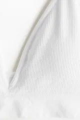Soutien suave sin costuras, color blanco, con diseño de punto acanalado, copas triangulares con relleno removible y tirantes finos ajustables.