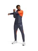 Pantalón deportivo Under Armour de la colección Challenger, color azul oscuro con detalles laterales en naranja. Presenta corte ajustado, cintura elástica con cordón, bolsillos laterales y cremalleras en los tobillos.