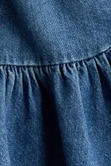 Pollera corta de denim de algodón rígido, con cintura estándar, cierre y botón, bolsillos delanteros y diseño acampanado con frunce.