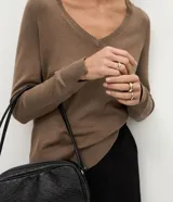 Blusa básica de punto leve color marrón, con escote en V, mangas largas y cuello con textura acanalada. Presenta un corte regular y diseño liso.