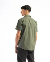 Camisa de manga corta color celeste claro, confeccionada en algodón, con cuello clásico y un bolsillo de parche en el lado izquierdo del pecho.