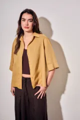 Camisa de lyocell color mostaza, de corte holgado, mangas cortas y cierre frontal con botones.