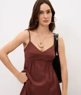 Vestido midi evasê marrón con breteles finos, escote corazón y corte en la cintura. Presenta silueta fluida con caída amplia y bolsillos laterales.