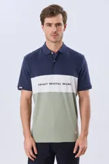 Remera polo de manga corta con diseño en bloques de color en tonos azul marino, blanco y verde militar, con bordado frontal y cierre de botones.