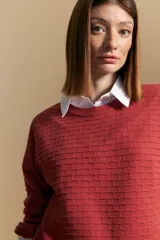 Sweater de mangas abullonadas con textura tejida en relieve, color rojo ladrillo. Su silueta es amplia con puños elastizados.