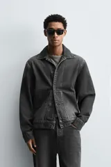 Sobrecamisa de corte regular confeccionada en denim de algodón con efecto lavado. Presenta cuello solapa, cierre frontal con botones, mangas largas con puños abotonados y bolsillos de vivo en la cadera.
