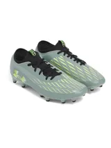 Championes de fútbol Under Armour Magnetico Select 4 FG, color verde grisáceo con detalles en amarillo neón y negro. Presentan una parte superior de piel sintética con estampado 3D para mayor control, cuello textil tipo calcetín y suela de TPU con tacos cónicos para tracción en césped natural.
