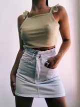 Crop top negro con textura brillante, breteles anchos con volados y espalda descubierta que se ata con lazos.