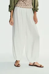 Pantalón blanco de tejido fluido, tiro medio con cintura elástica y bajo abullonado.