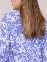 Blusa azul con estampado tipo pincelada en tonos blancos, cuello solapa con escote en V, media abotonadura frontal con botones nacarados, mangas tres cuartos con puños elásticos y diseño semi holgado.