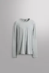 Camiseta térmica de manga larga color gris claro, confeccionada en tejido elástico con lana. Cuenta con cuello redondo y es transpirable y termorreguladora.