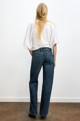 Jeans de mezclilla azul oscuro con efecto lavado, tiro bajo y pierna ancha extra larga. Modelo de cinco bolsillos con cierre frontal de cremallera y botón metálico.