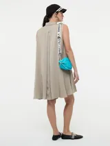 Vestido camisero corto color beige, sin mangas, con cuello clásico, cierre frontal con botones y bolsillos laterales.