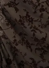 Vestido largo marrón con diseño asimétrico de un solo hombro, confeccionado en tela de terciopelo con estampado flocado de motivos florales y botánicos.