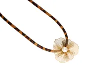 Collar con correa de cuerina con estampado animal print (leopardo/guepardo) y dije central con forma de flor calada en metal dorado, con una perla blanca en el centro.