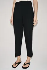 Pantalón de tiro medio con cintura con trabillas, detalle de raya planchada y bajo con aberturas laterales. Cierre frontal con cremallera, botón y ganchos metálicos.