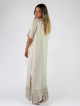 Vestido largo bordó de punto metalizado, con escote en V, mangas cortas y detalle de flecos en el ruedo.