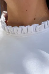 Remera de manga larga color blanco, confeccionada en algodón, con detalle de volados en los puños.