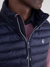Chaleco acolchado azul marino confeccionado en nylon reciclado repelente al agua, con diseño slim fit, cremallera central y bolsillos laterales.