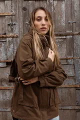 Gabardina liviana color beige con capucha, cierre frontal oculto y cintura ajustable mediante cordón. Presenta bolsillos delanteros amplios y mangas largas con puños rectos.