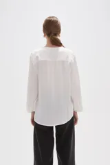 Blusa de viscosa color blanco, con cuello en V, manga 3/4 y bolsillo frontal en el pecho.