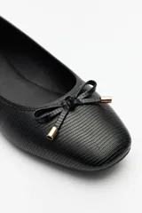 Balerinas negras de símil cuero texturizado con aplique de moña y detalles metálicos.