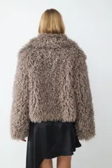 Campera corta de pelo sintético con textura rizada y voluminosa, de corte holgado y diseño envolvente.