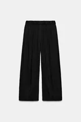 Pantalón de tiro medio con cintura elástica y pierna ancha. Presenta bolsillos laterales ocultos en la costura y un diseño fluido.